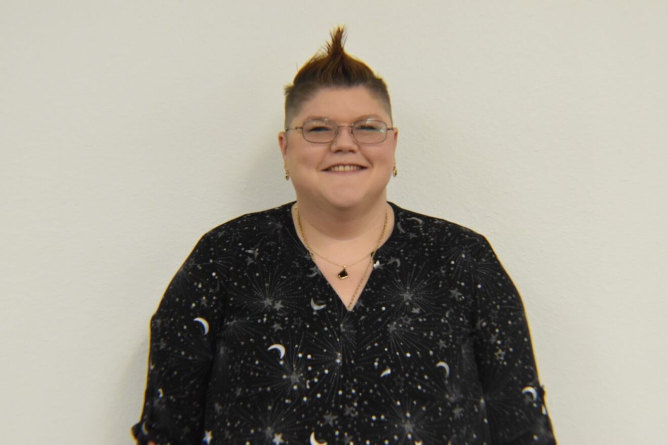 A person smiling with a mohawk hairstyle against a white background.
