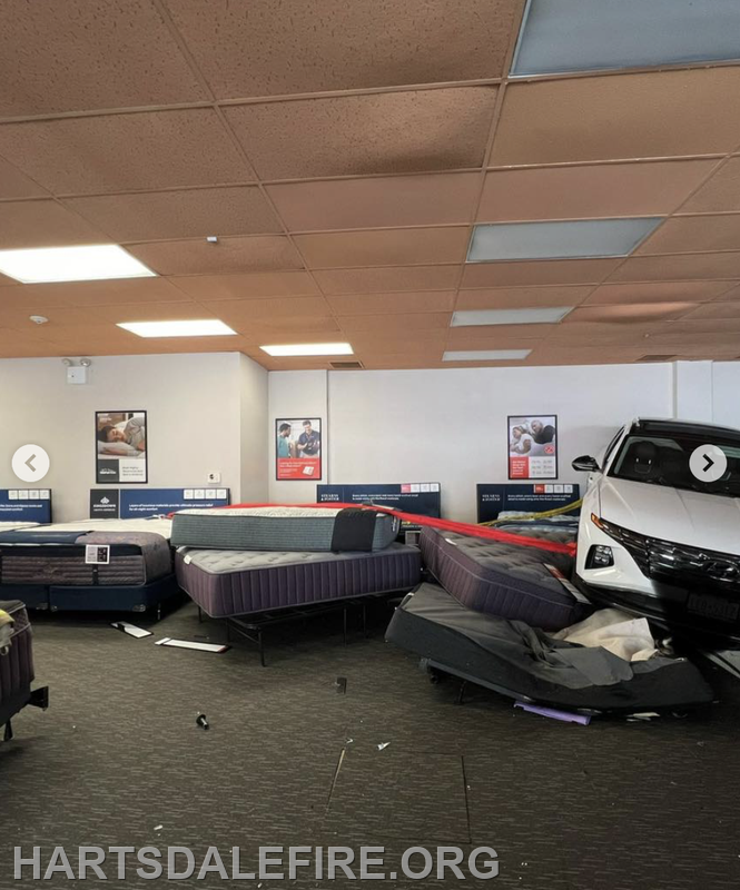 A car has crashed into a mattress store, causing mattresses to be pushed around in the aftermath.