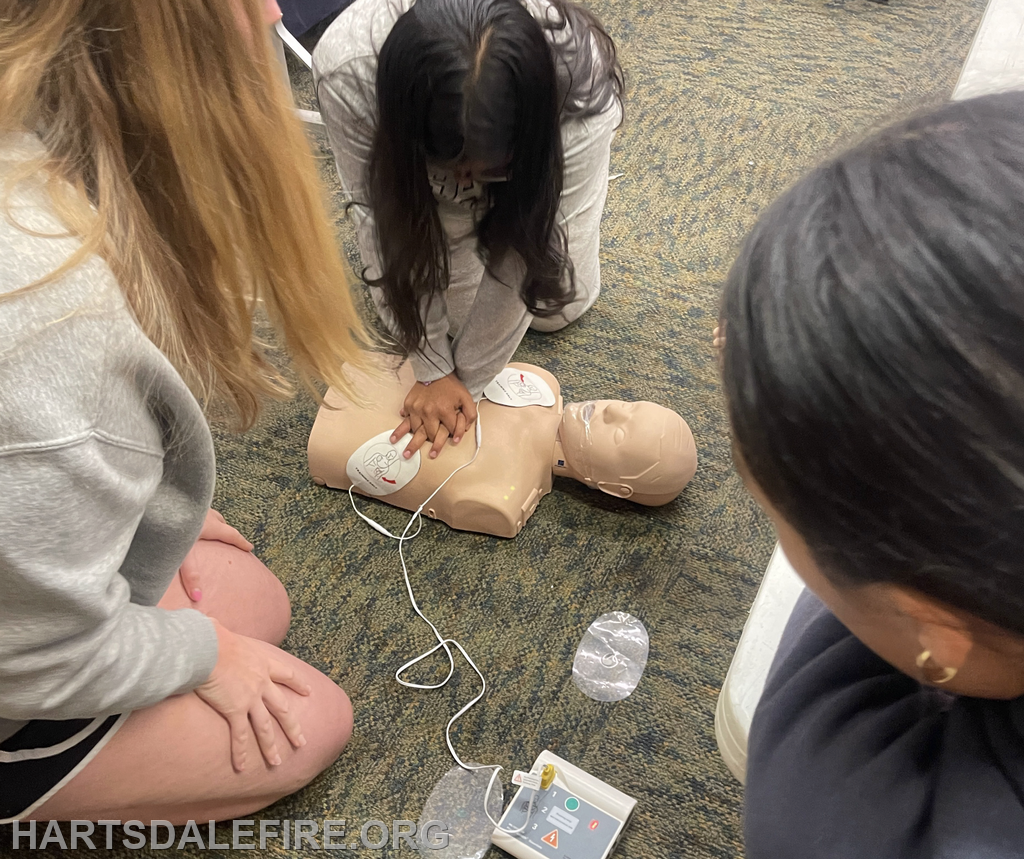 Several people practicing CPR on a training mannequin, focusing on chest compressions and using an AED device.