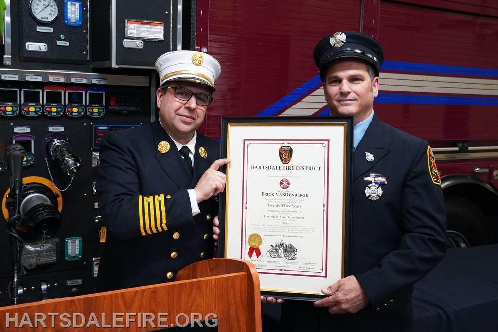 Two firefighters pose with a certificate award.
