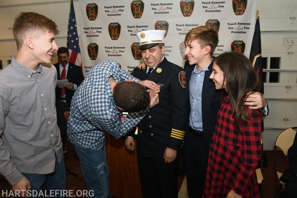 A group of people, including a firefighter, laughing and smiling at a ceremony.