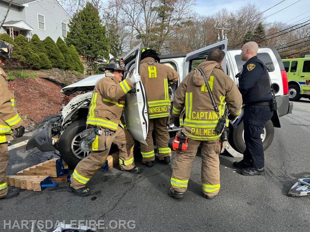 Firefighters and police are responding to a vehicle accident, working to assist or extract someone from a damaged SUV.