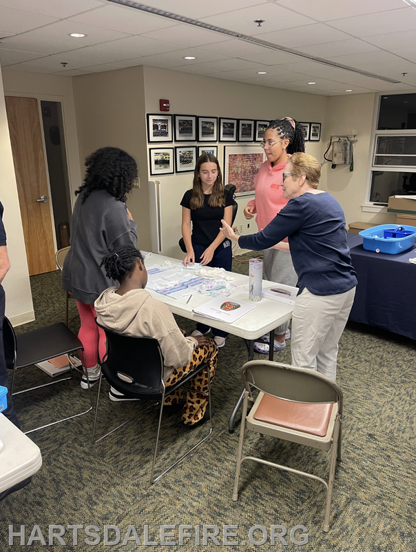 A group of people is gathered around a table, engaging in a collaborative activity, possibly a craft or educational session.