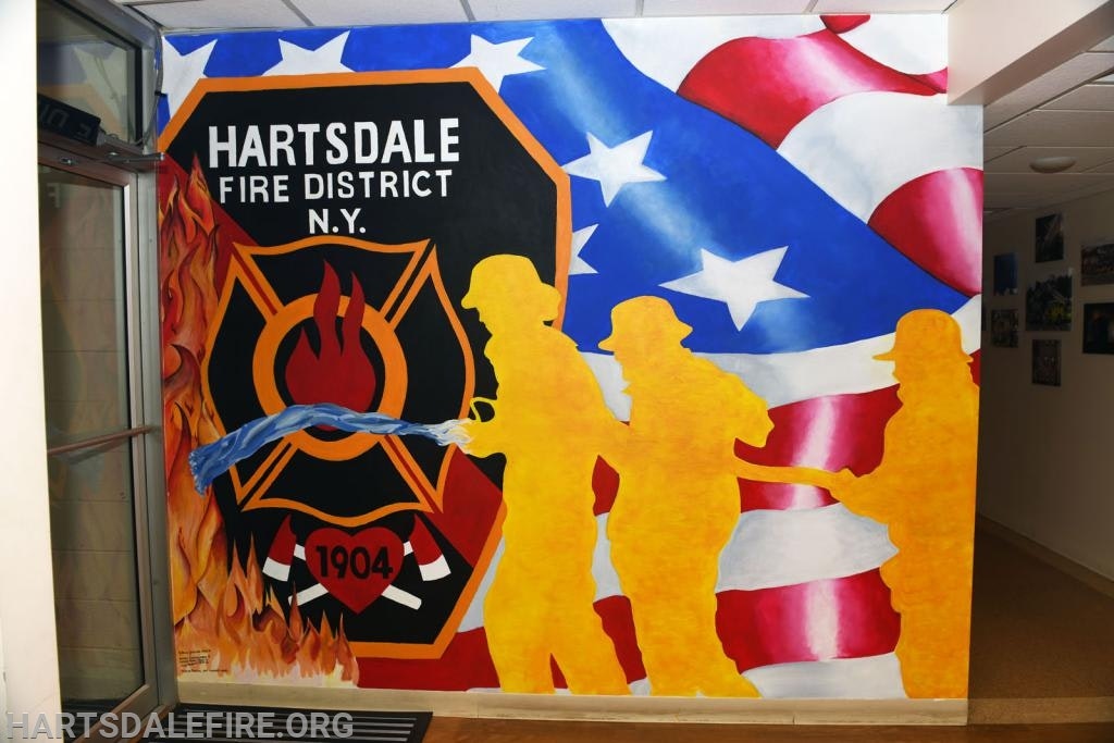 Mural of Hartsdale Fire District logo, USA flag, and yellow silhouettes of firefighters holding a hose.