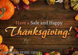 "Have a Safe and Happy Thanksgiving" message with autumnal decorations on wooden background.