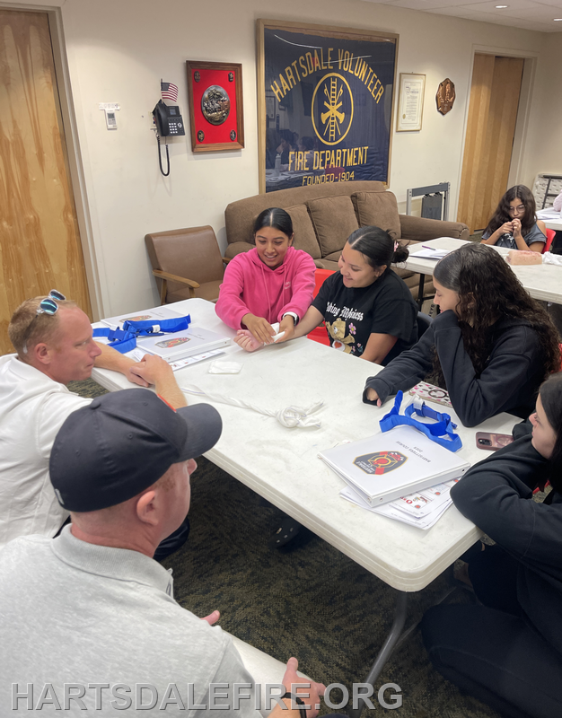 A group of people gathered around a table at the Hartsdale Fire Department, engaged in a learning or training session.