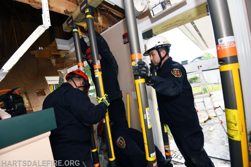 Firefighters using support poles to stabilize a damaged structure.