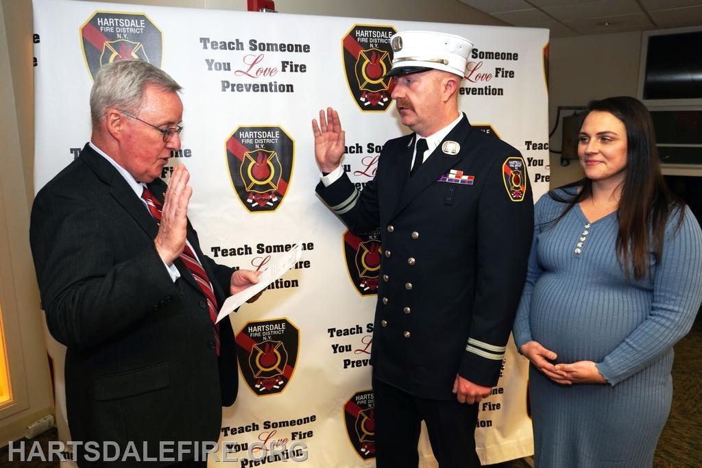 A fire official is being sworn in with support from a pregnant woman at an event promoting fire safety in Hartsdale.