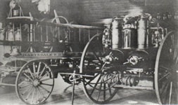 A vintage horse-drawn fire engine with large wheels and metallic tanks, from an early fire department.