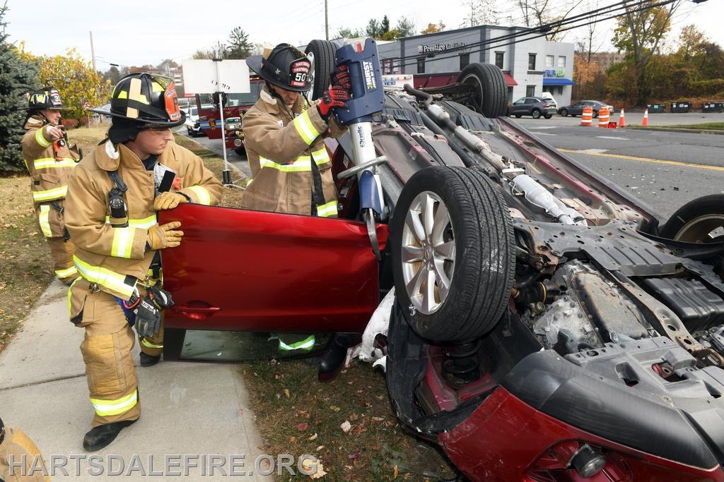 Firefighters responding to an overturned car accident, working to rescue anyone trapped inside.
