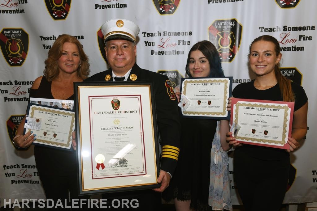 Four people holding certificates from the Hartsdale Fire District.