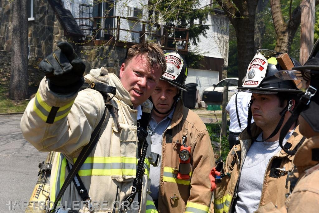 Firefighters are discussing a situation outdoors, focused and communicating about the task at hand.