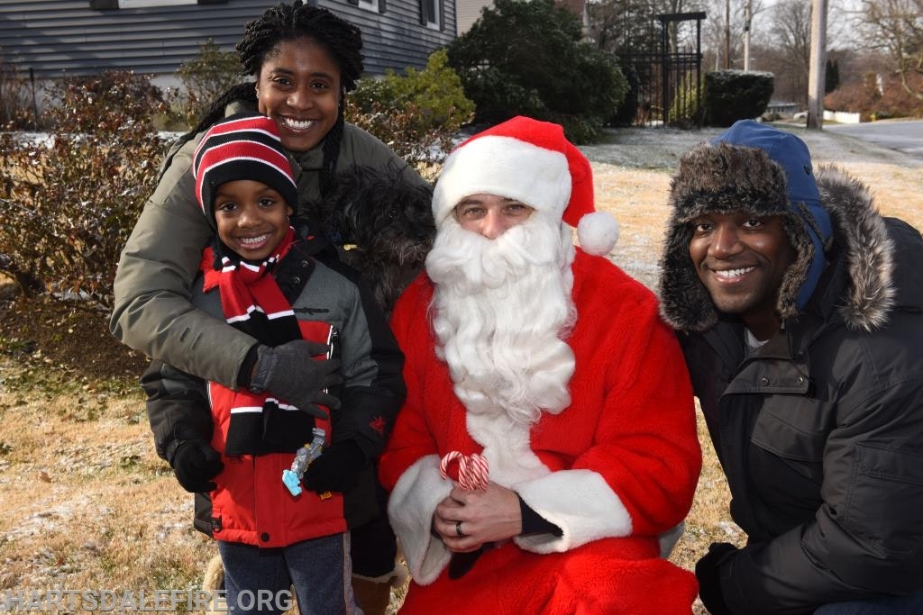A group of people outdoors, one dressed as Santa, posing happily.
