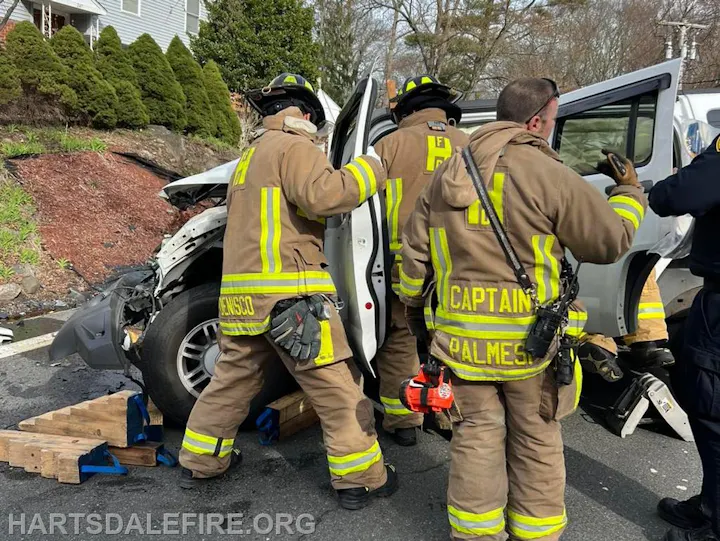 Firefighters are responding to a vehicle accident, working to assist with the situation near a residential area.