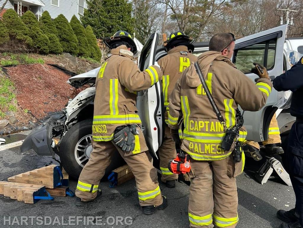 Firefighters are responding to a vehicle accident, working to assist with the situation near a residential area.