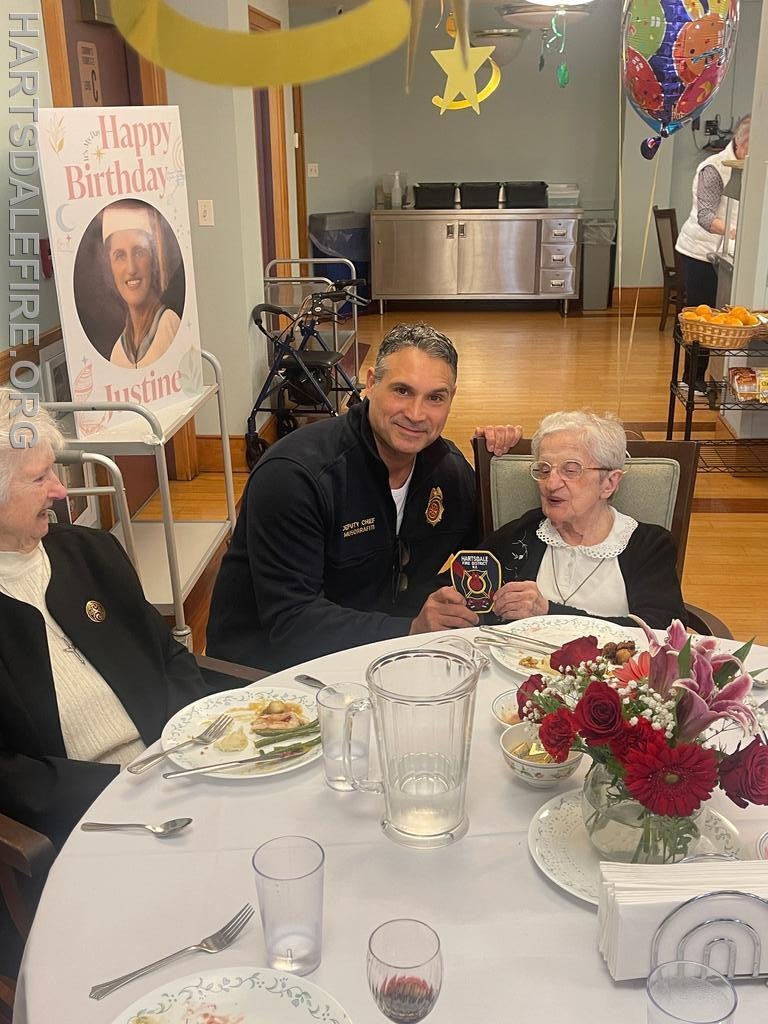 A birthday celebration for Justine with guests, a decorated table, and balloons in a warm, festive setting.