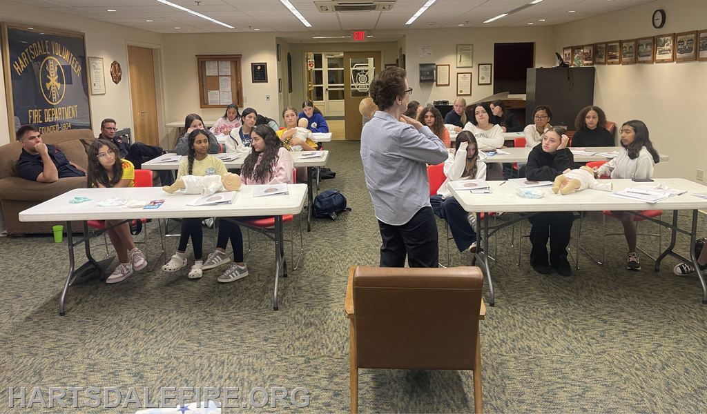 A group of young people attends a classroom session, likely learning about safety or emergency procedures, guided by an instructor.