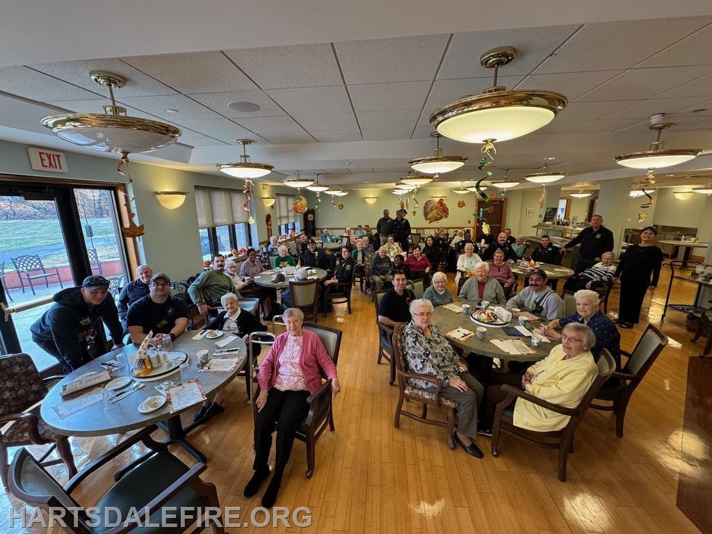 A gathering in a dining area with elderly residents and staff, celebrating a festive event together.