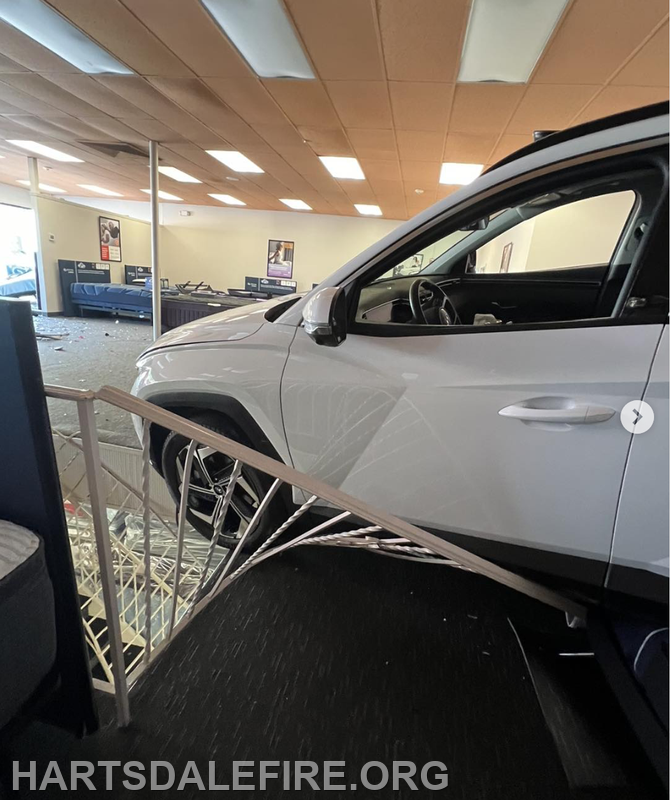 A car has crashed into a store, causing damage and debris inside.