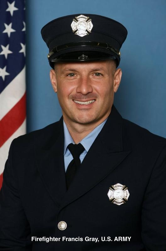 A smiling firefighter in uniform, facing the camera, with an American flag in the background.
