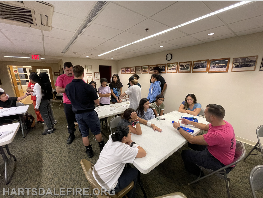 A group of children and adults engage in an activity or workshop at a community center, featuring tables and discussion.