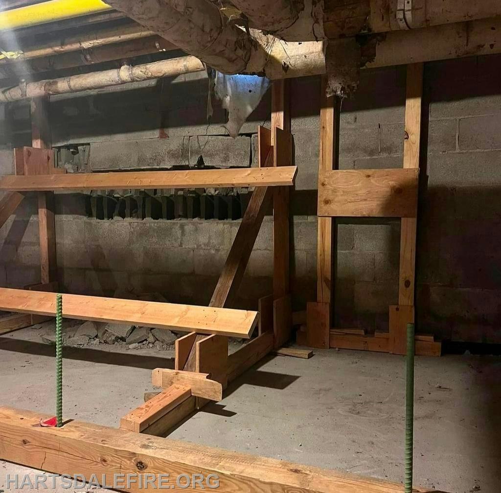 Wooden supports under a damaged ceiling with pipes.