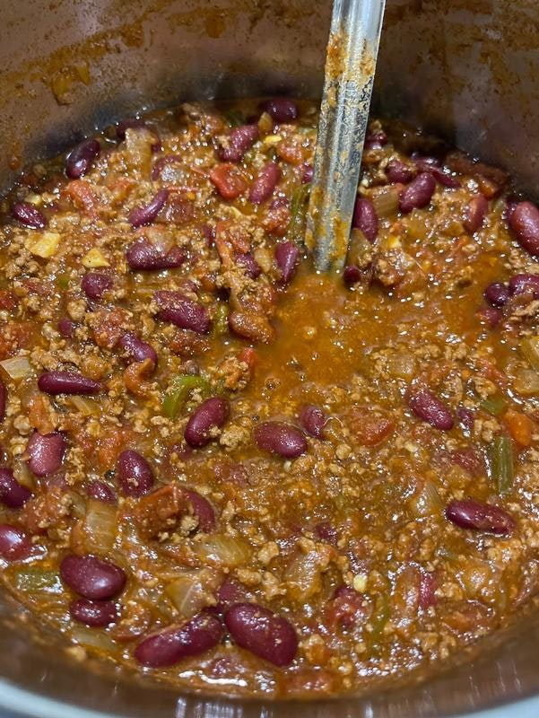 A pot of chili featuring ground meat, kidney beans, tomatoes, and spices, simmering together.