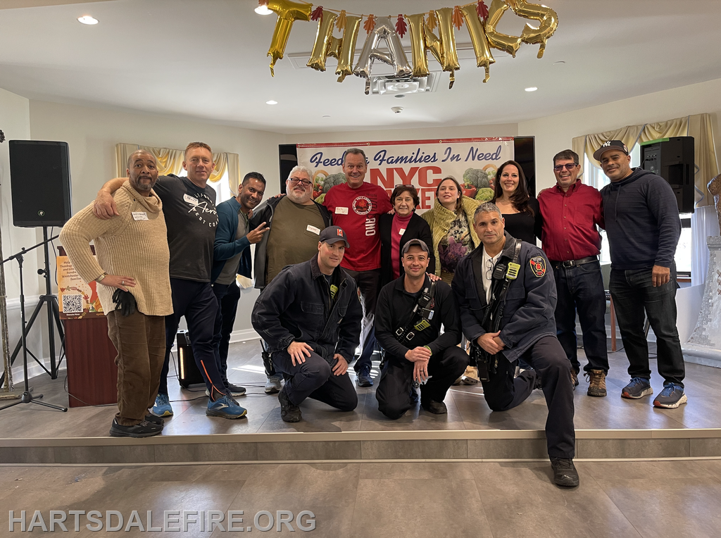 A group of people, including firefighters, gather at an event to support families in need, with "Thanks" displayed above.