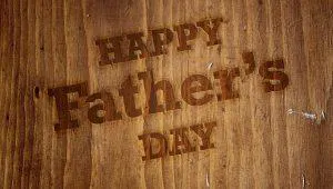 The image shows the text "Happy Father's Day" on a wooden background.