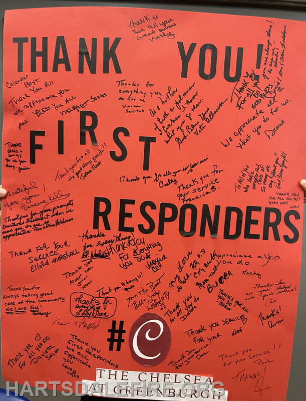 A large red poster with messages of gratitude for first responders, featuring various signatures and thanks from the community.