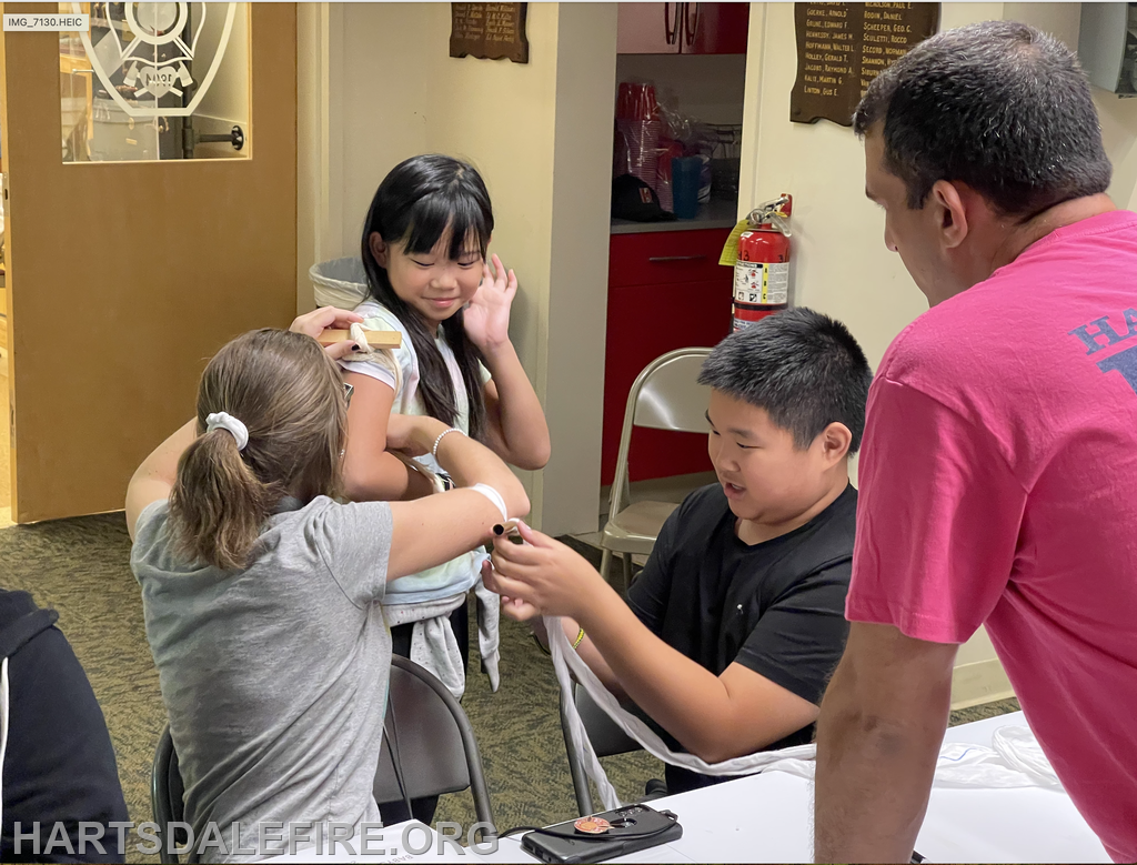 Children practicing basic first aid techniques in a classroom setting, guided by an adult.