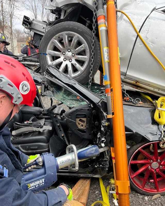 The image shows a multi-vehicle accident scene with a firefighter using tools to assist in rescue efforts.