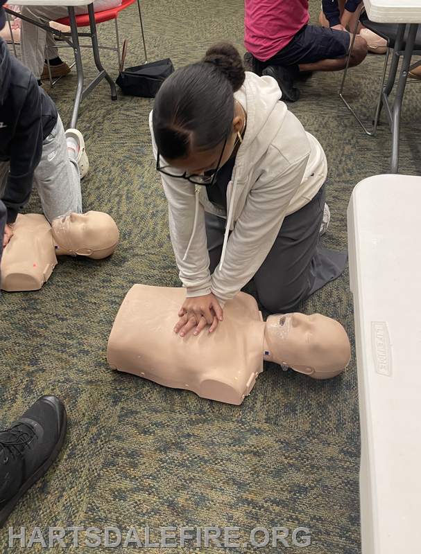 A person is practicing CPR on a dummy in a training setting, demonstrating lifesaving techniques.