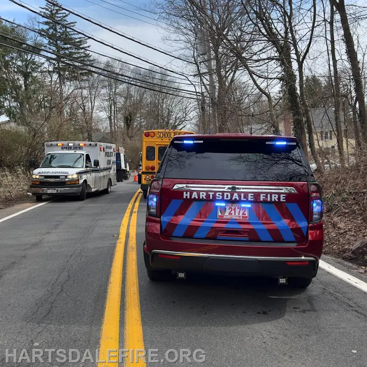 Emergency vehicles on a road, including a fire truck, police vehicle, and an ambulance near a school bus.