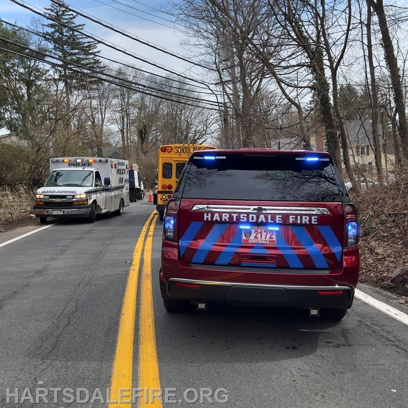 Emergency vehicles on a road, including a fire truck, police vehicle, and an ambulance near a school bus.
