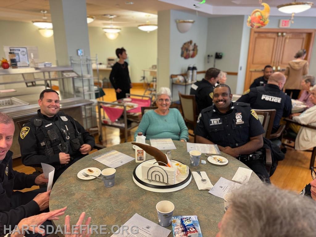 A group of police officers and seniors gather around a table, enjoying food and conversation in a community setting.
