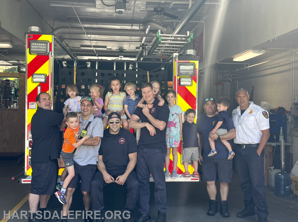 A group of firefighters and children pose together in front of a fire truck, celebrating community engagement.
