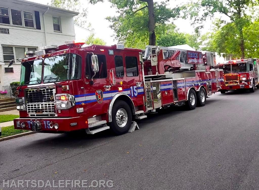 Red fire truck marked "15" with ladders, parked on a residential street.