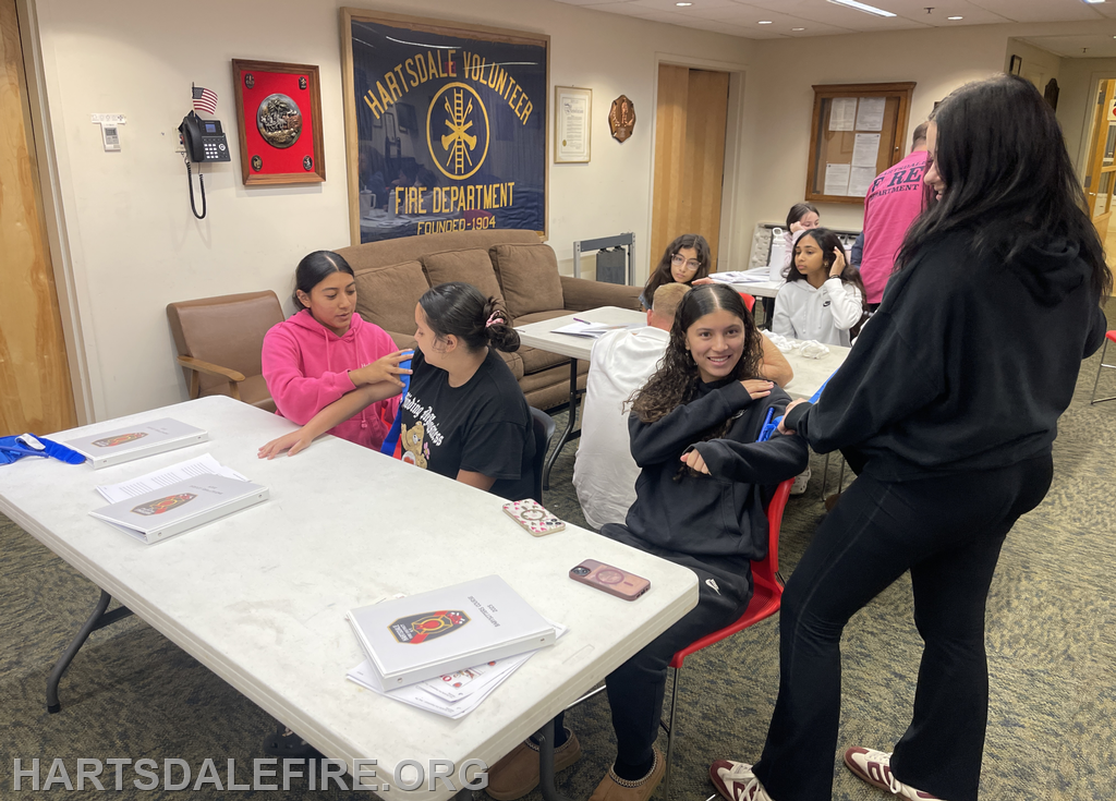 A group of young people engaged in activities at a fire department facility, with educational materials on the table.