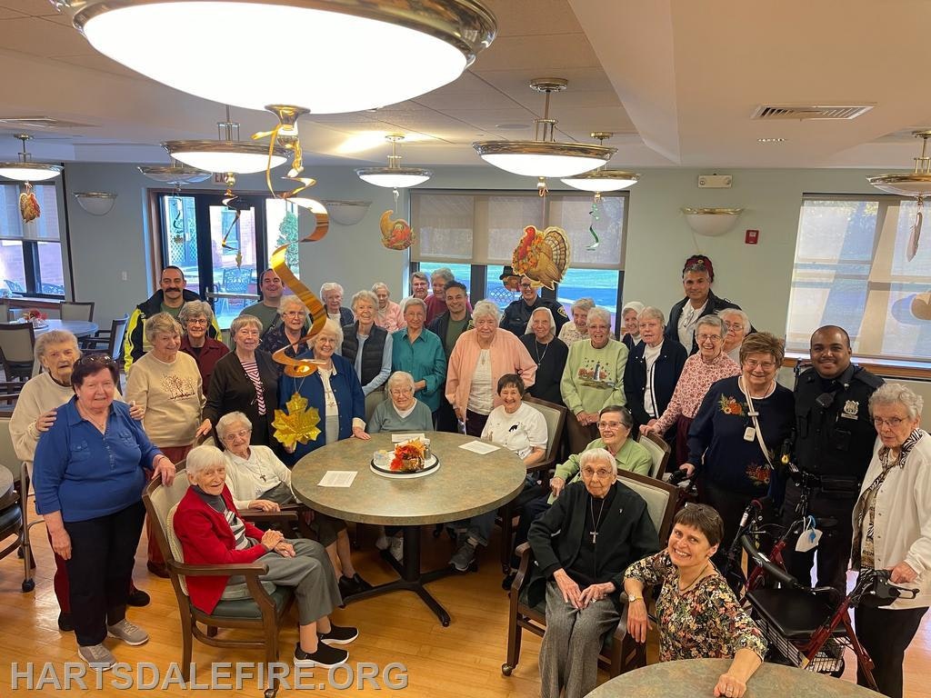 A group of elderly residents and staff, including police officers, gather together in a festive setting.