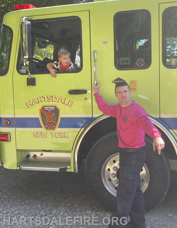 A child sits in a fire truck, while a firefighter poses outside the vehicle, both in bright colors.
