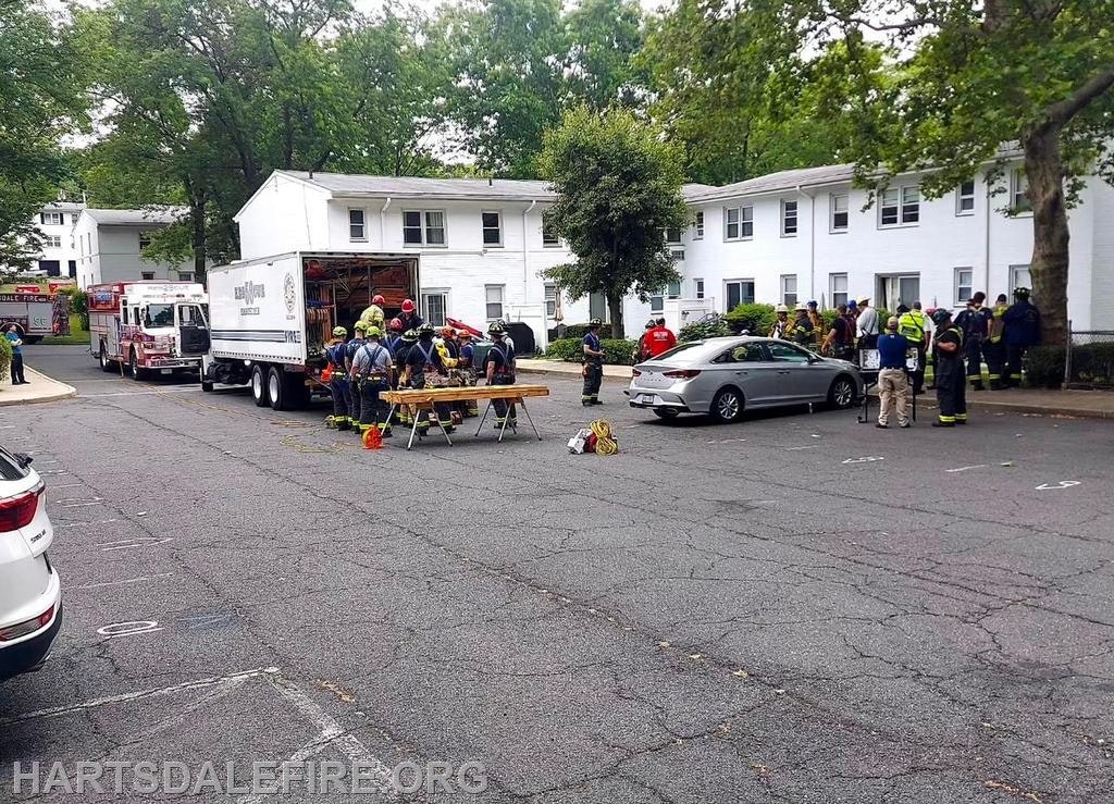 Firefighters gathered near fire trucks and equipment in a residential area.