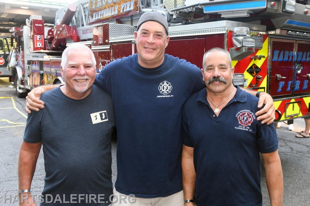 Three men pose together in front of a fire truck, showcasing camaraderie and a shared connection to firefighting.