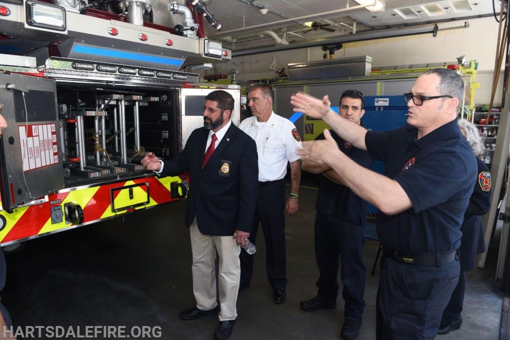 Group of people at a fire station inspecting equipment on a fire truck.