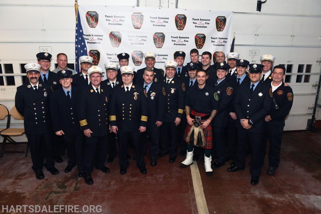 A group of firefighters posing for a photo indoors, with banners promoting fire prevention in the background.