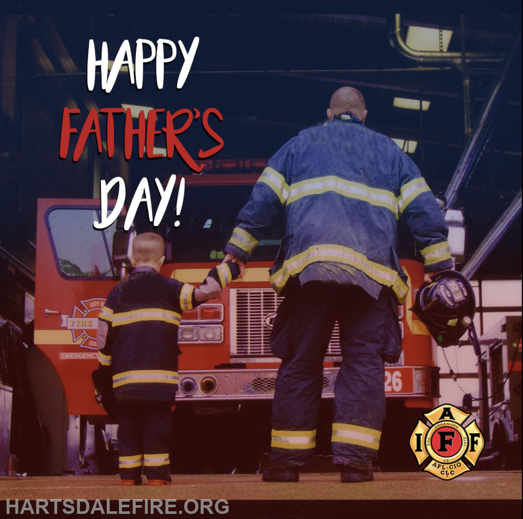 A firefighter holds hands with a child in front of a fire truck, celebrating Father's Day with a festive message.