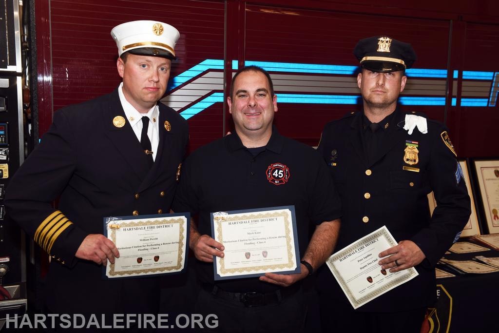 Three men in uniform holding certificates from the Hartsdale Fire District, likely for commendation or achievement.