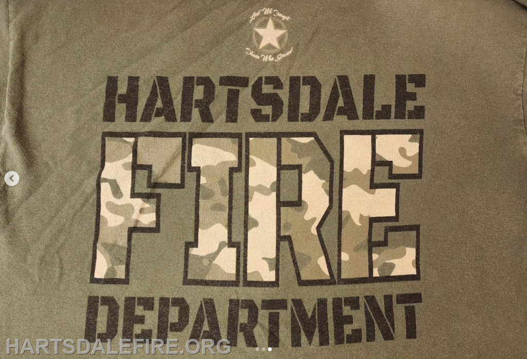 The image features a shirt with "Hartsdale FIRE DEPARTMENT" in bold letters, with a camouflage pattern on "FIRE."