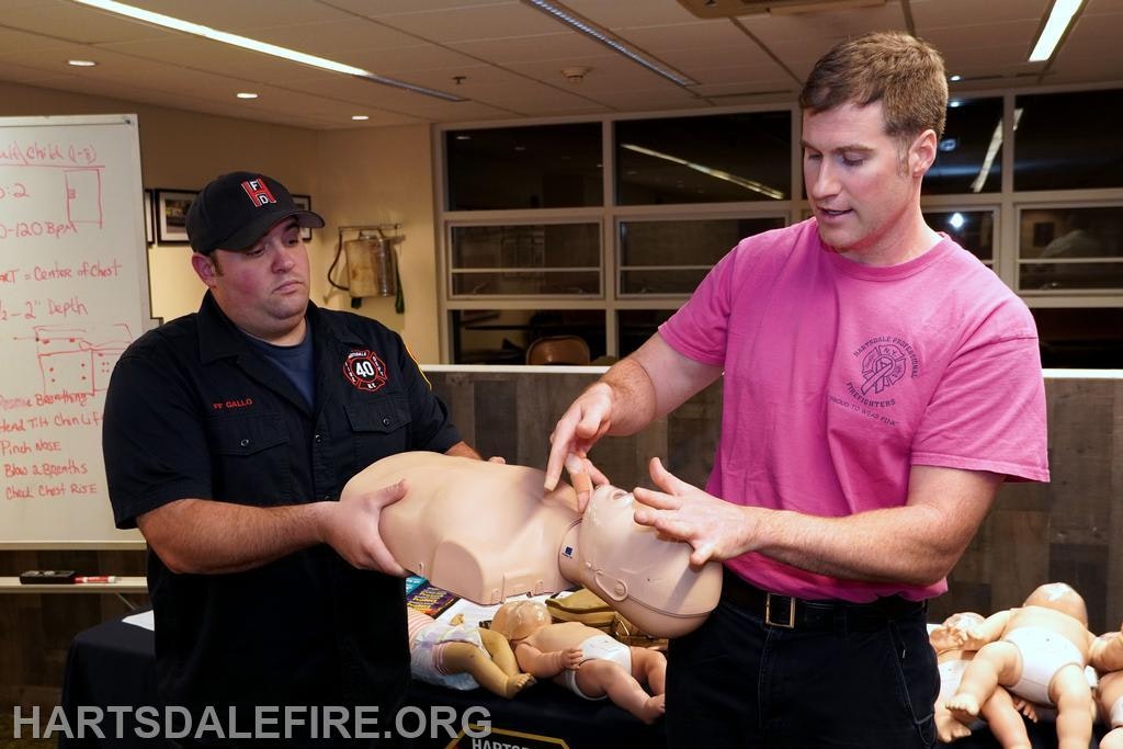 Two people demonstrating CPR on a training mannequin.