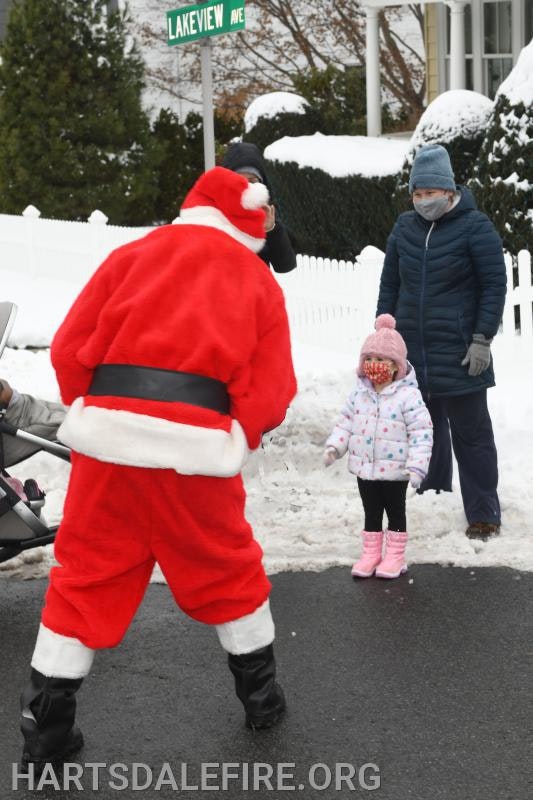 Santa interacts with children and adults in a snowy street scene, with a street sign reading "Lakeview Ave."